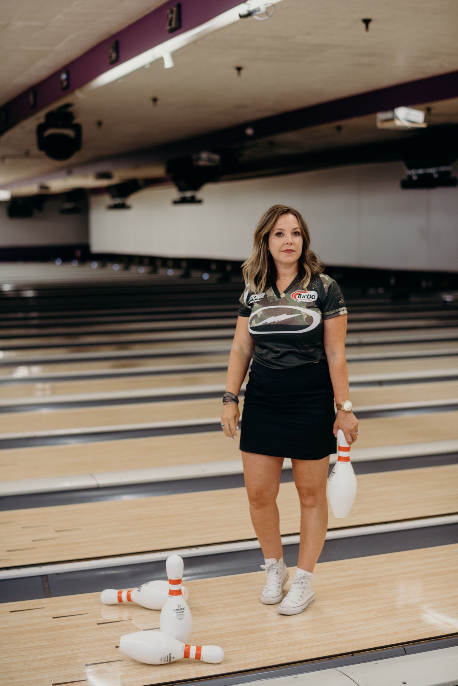 Diandra Asbaty on the approach holding a bowling pin, on the lanes